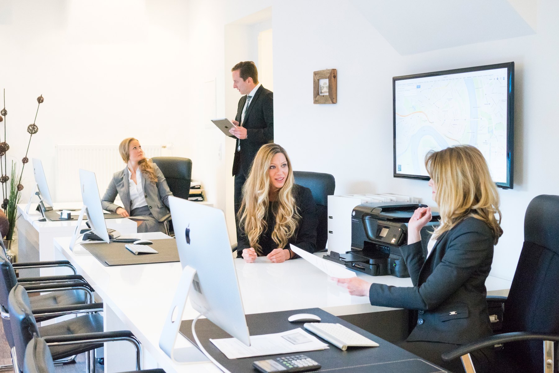 Mehrere Personen besprechen Unterlagen und arbeiten in einem Büro.